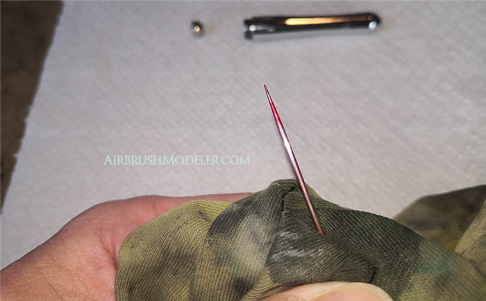 Nach dem Entfernen der Nadel werden Sie wahrscheinlich Farbreste am Ende der Nadel bemerken. Dieser Schritt zeigt, warum das einfache Spülen der Airbrush nicht ausreichend ist, um alle Farbreste zu entfernen.